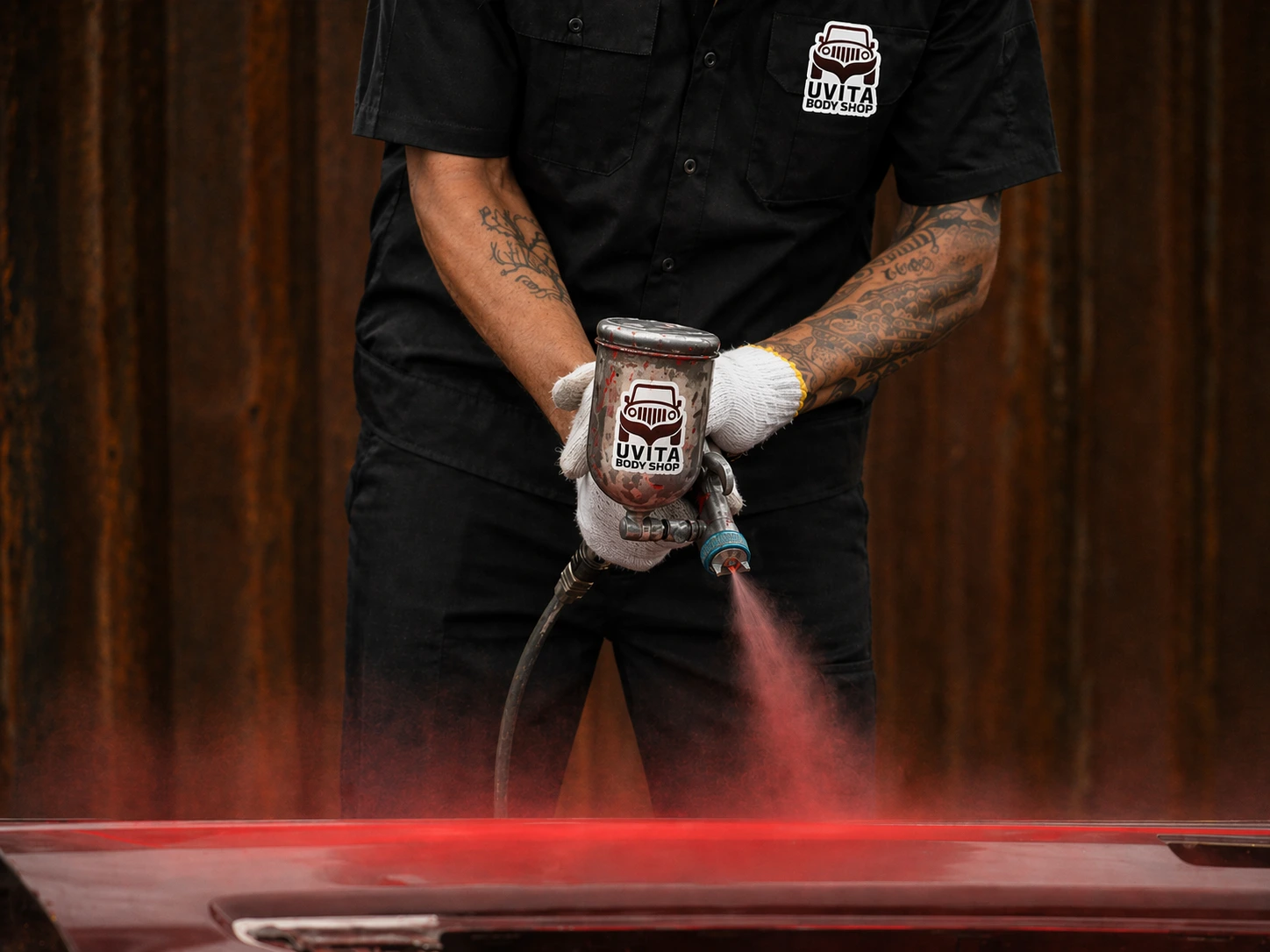 Uvita Body Shop technician spraying a vehicle with an HVLP gun in the controlled booth