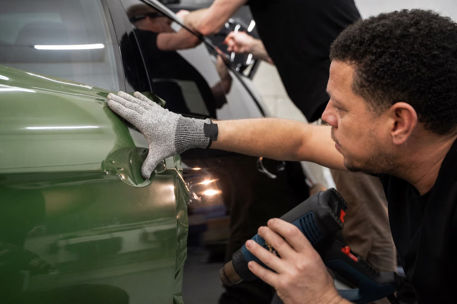 Técnico trabajando reparación de abolladura en un panel lateral del vehículo